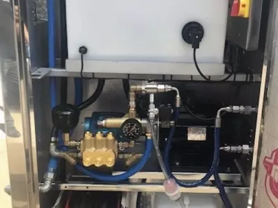 Internal view of the bespoke wheel wash system showing the CAT pump, inlet water tank, chemical setup, and integrated hose reel. Designed for reliability, ease of maintenance, and a clean, organised layout within the stainless steel cabinet.